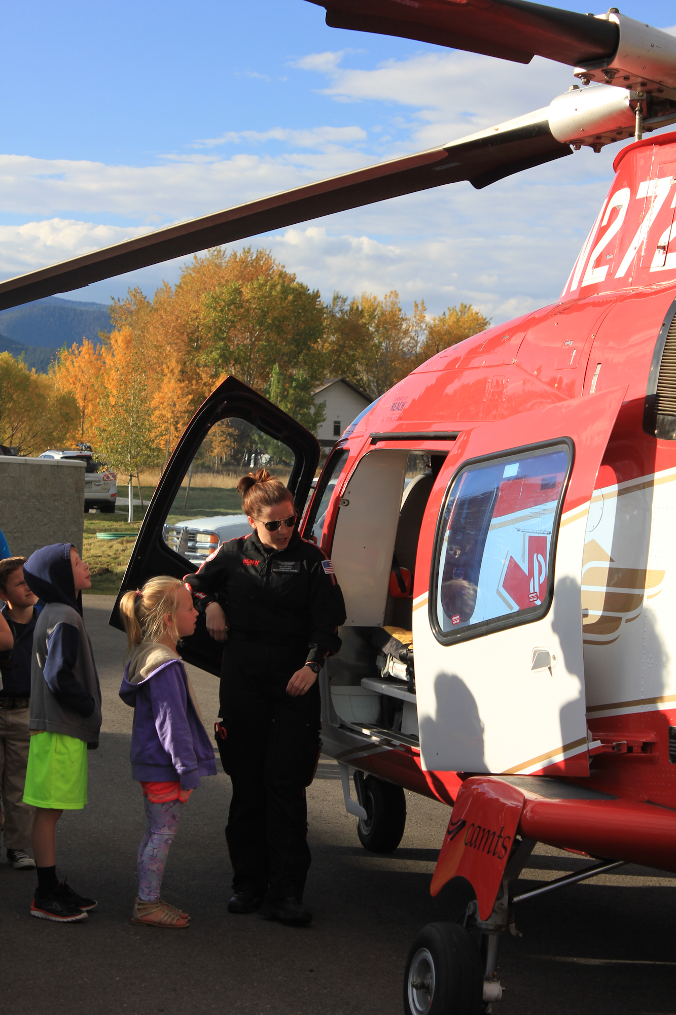 A helicopter demonstration for kids, featuring a pilot interacting with them and an open helicopter door.
