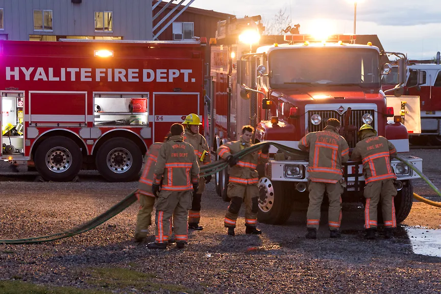 Firefighters from the Hyalite Fire Department prepare equipment near their fire truck during dusk.
