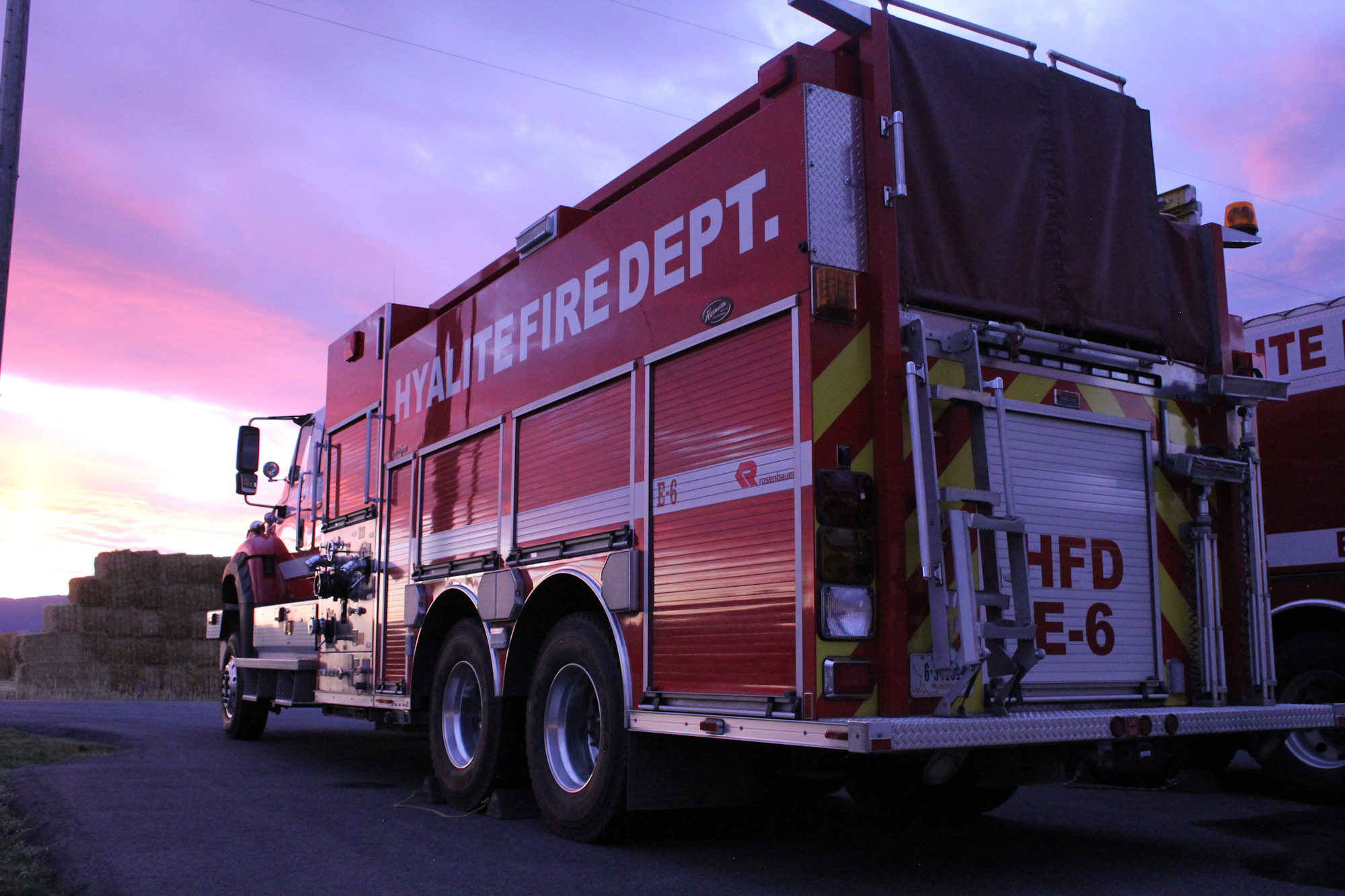 The image features a fire truck from the Hyalite Fire Department, parked on a road with a colorful sunset in the background.