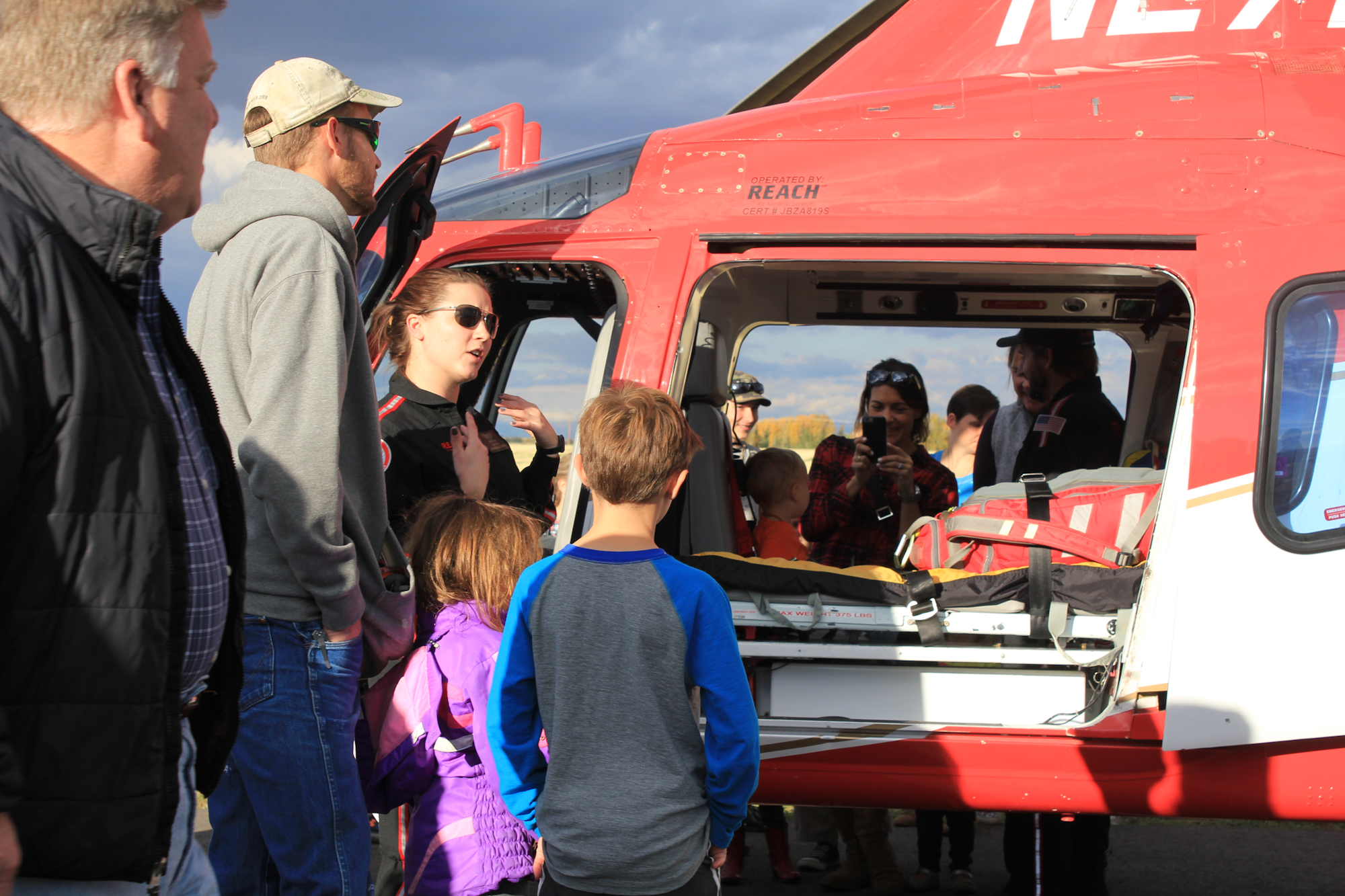 A crowd, including children, interacts with a helicopter and its crew during an event, likely focused on emergency services.