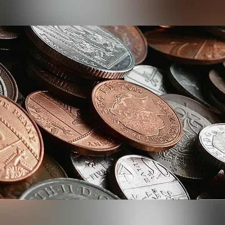 The image shows a collection of various coins, including copper and silver types, stacked and scattered together.