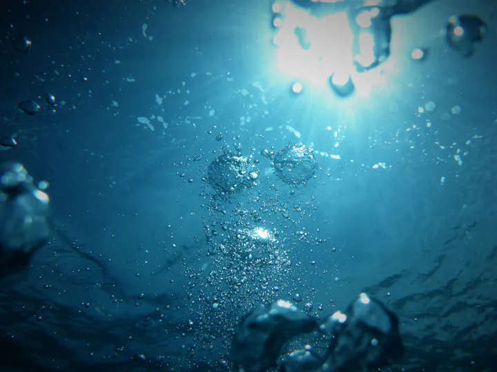 An underwater scene featuring sunlight filtering through water, with bubbles and a blue ambiance.