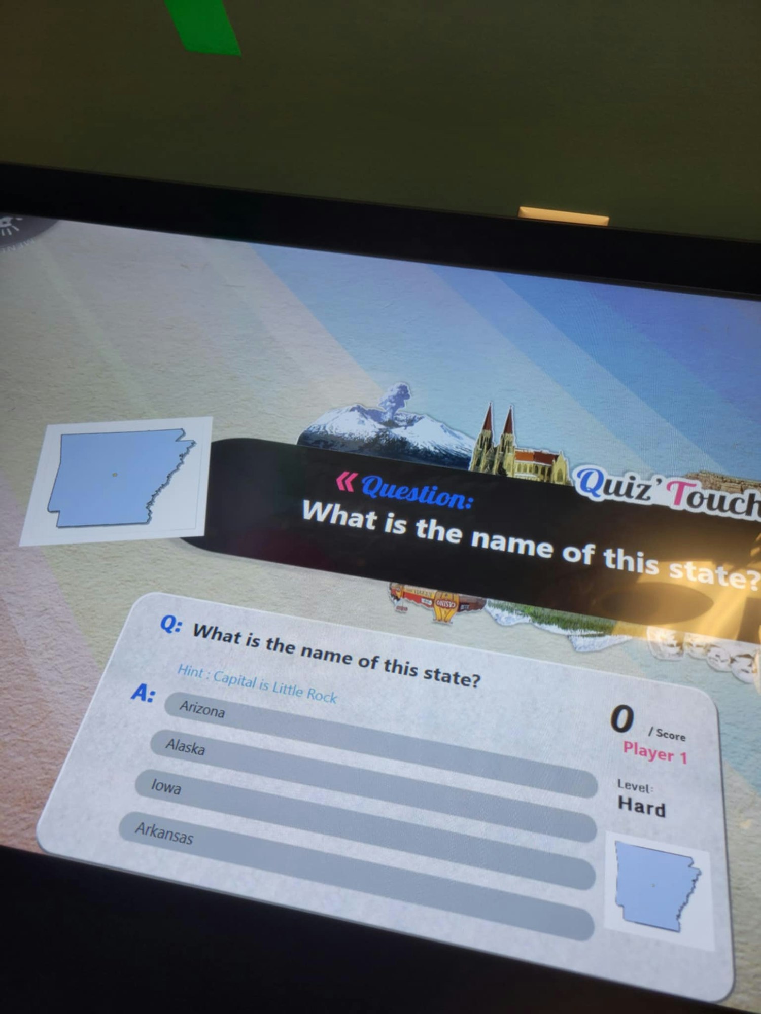 Quiz screen asking for the name of a state with the capital Little Rock; options: Arizona, Alaska, Iowa, Arkansas.