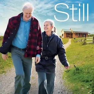 A happy elderly couple walks together on a scenic path, with a cozy home in the background and the word "Still" displayed.