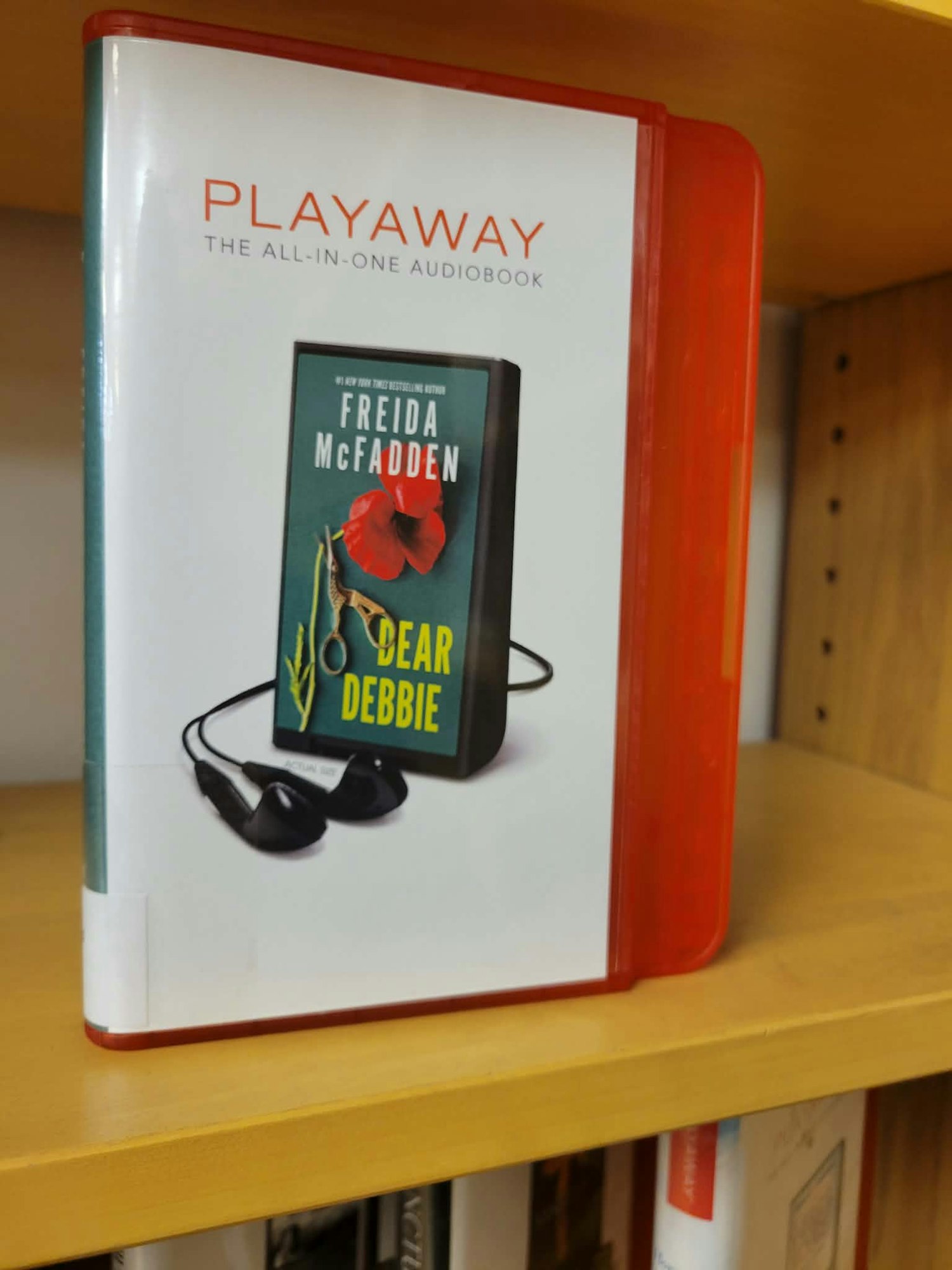 A Playaway audiobooks case featuring "Dear Debbie" by Frieda McFadden, complete with headphones.