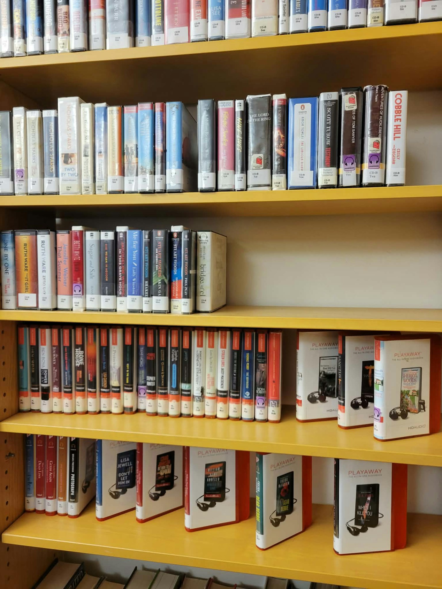 A library shelf displaying various audiobooks and Playaway devices.