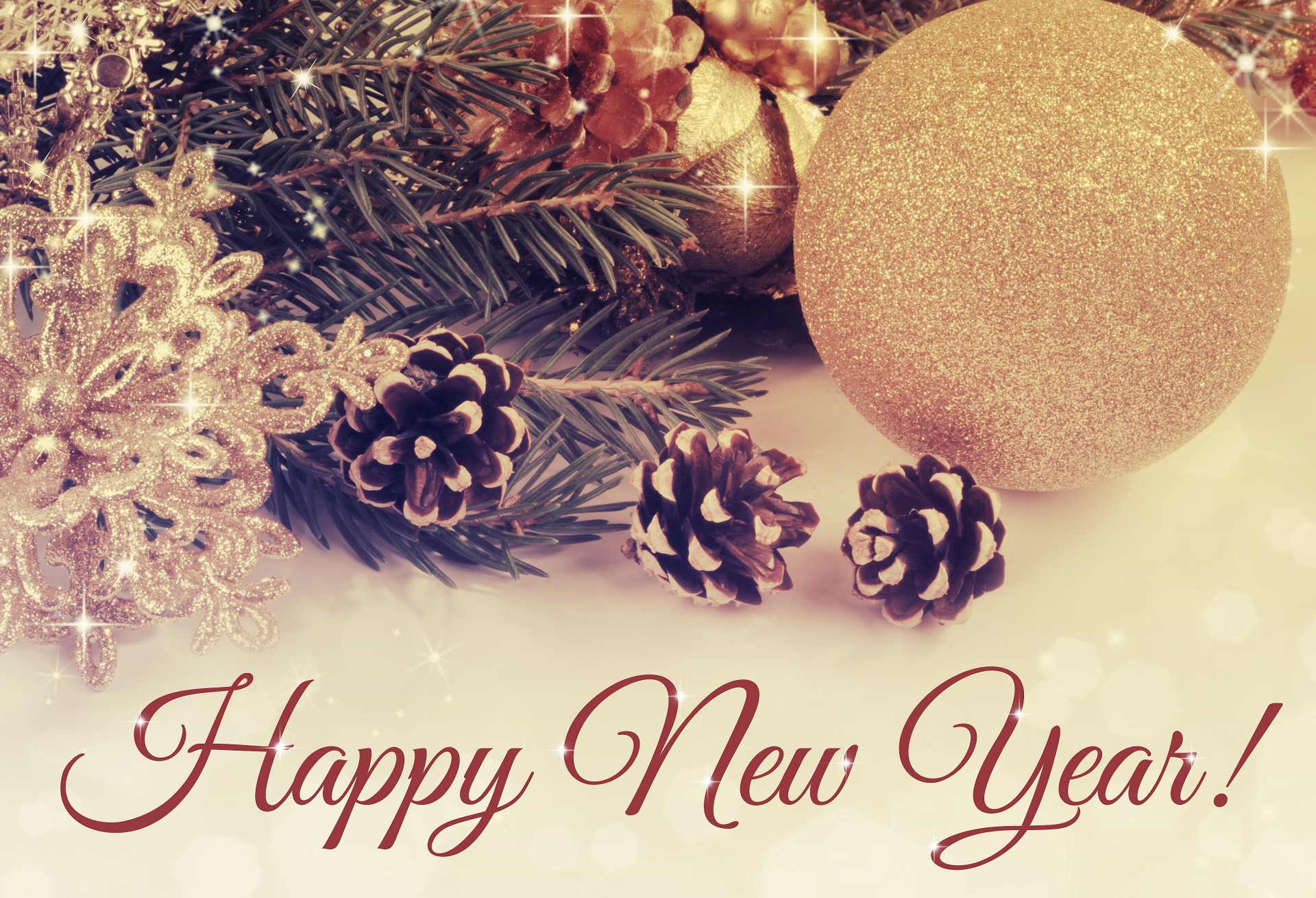 A festive arrangement featuring pinecones, gold ornaments, and a "Happy New Year!" message.