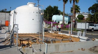 The image shows tanks and construction materials at a site, likely involving industrial or utility infrastructure.