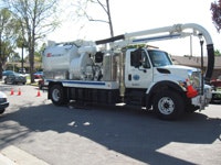 The image shows a large vacuum truck parked on a street, likely used for cleaning or maintenance purposes.