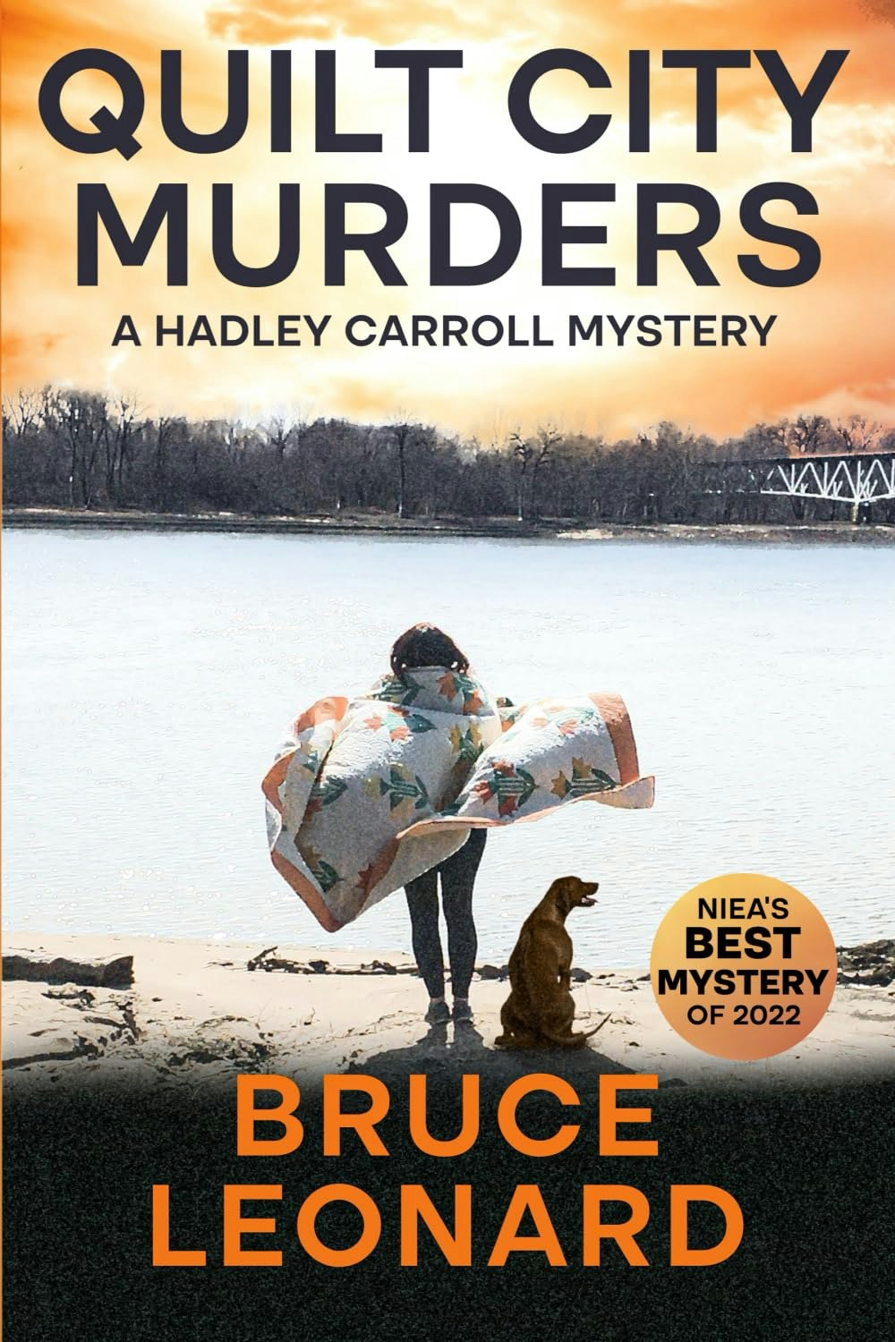 Book cover: "Quilt City Murders" by Bruce Leonard, featuring a lakeside scene with a person and a dog, and an award label for best mystery.