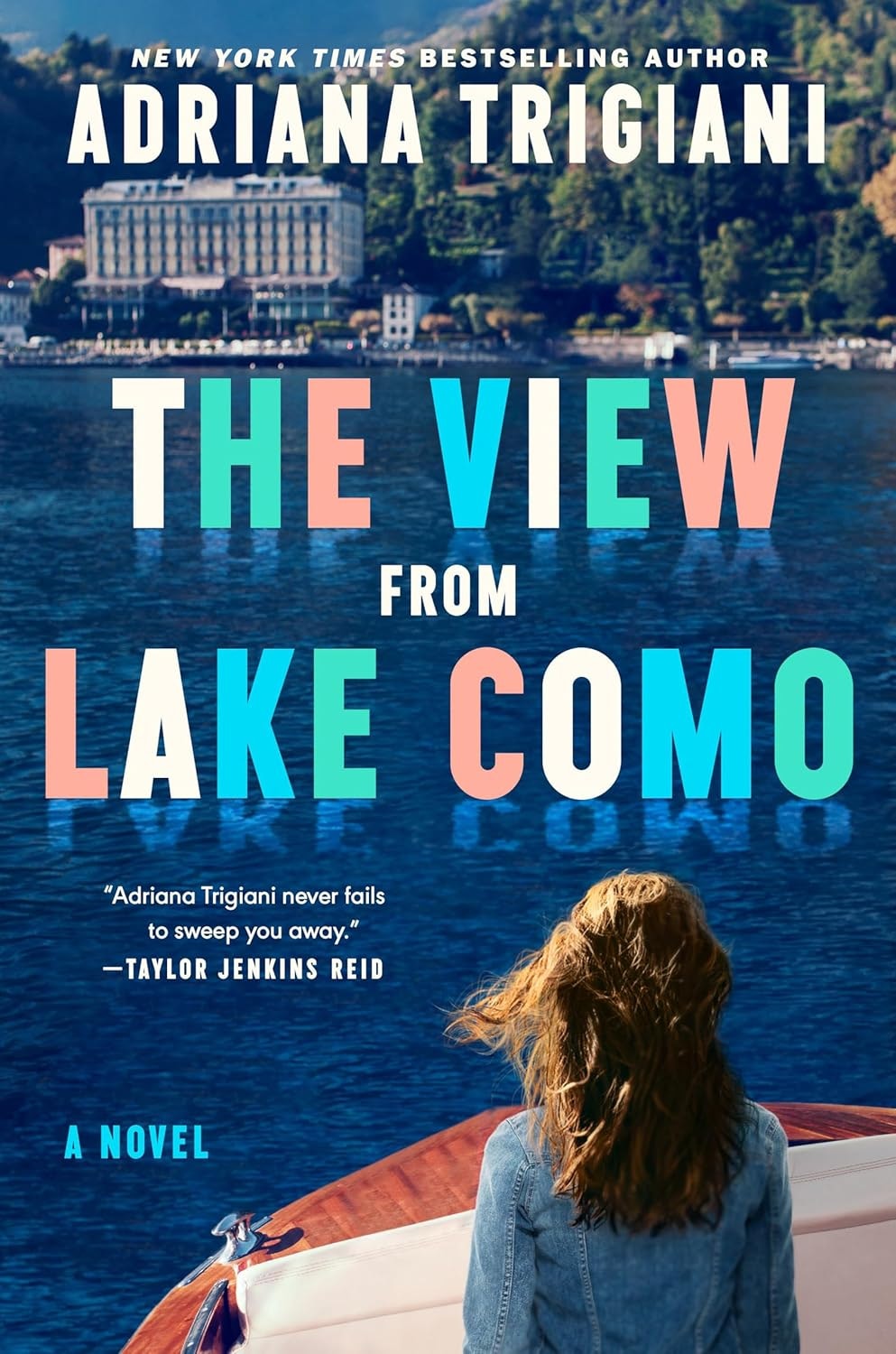 Book cover: "The View from Lake Como" by Adriana Trigiani. Woman on boat, scenic lake, and building; praised by Taylor Jenkins Reid.