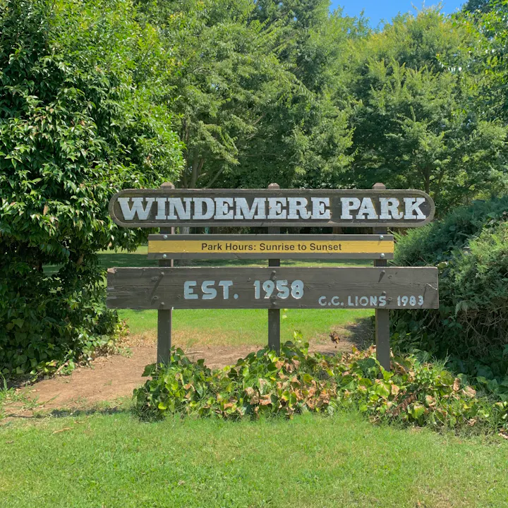 The image shows a sign for Windemere Park, established in 1958, with park hours from sunrise to sunset.