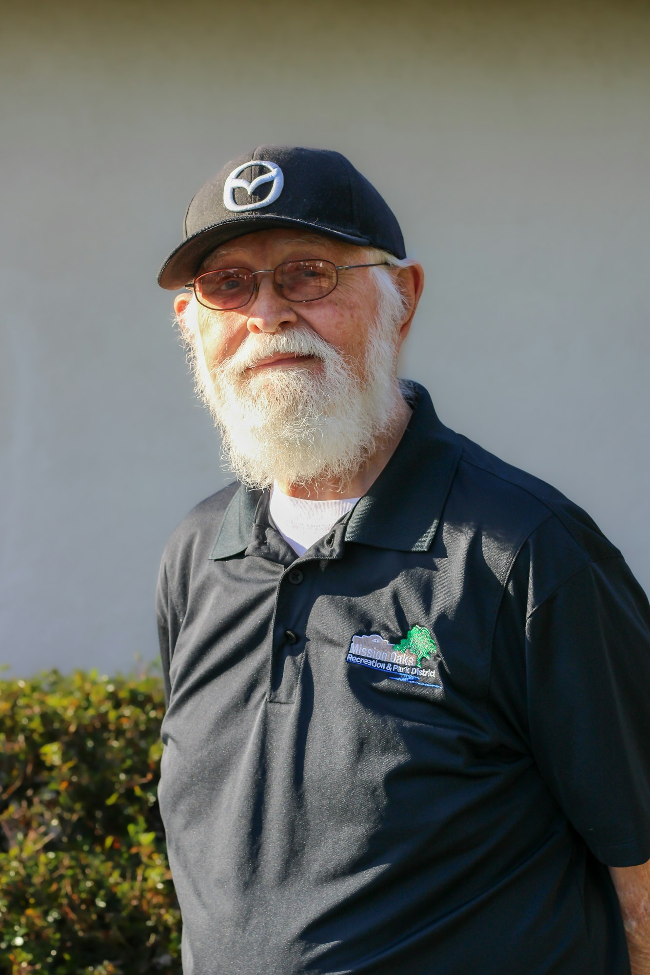 A bearded man wearing glasses, a cap with a logo, and a black polo shirt with "Mission Oaks Recreation & Park District" on it.