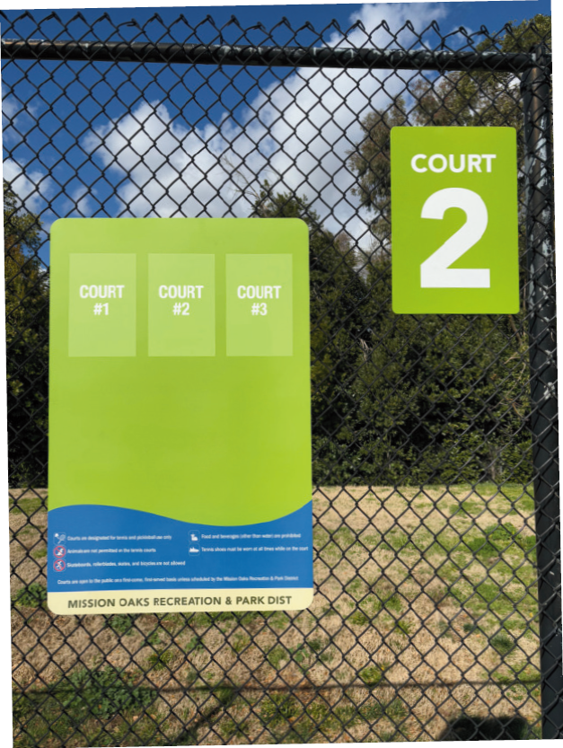 A sign on a fence indicates "Court 2" and lists courts #1-3 with park rules: tennis only, no pets, proper shoes required.