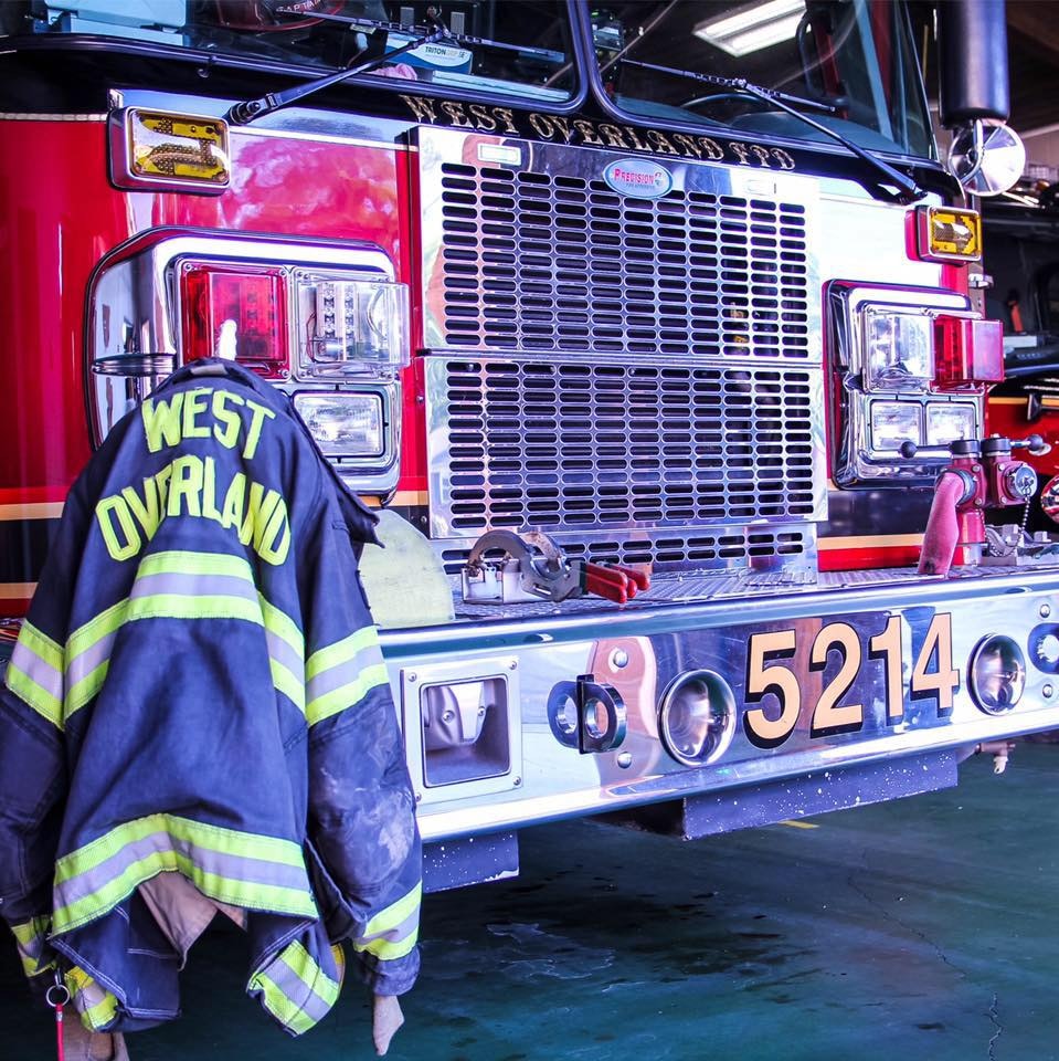 A fire truck with the phrase "WEST OVERLAND" and a firefighter's jacket hanging on the front.