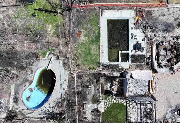 Aerial view of a damaged property with a debris-filled area, two pools, one with water, surrounded by burned and green sections.