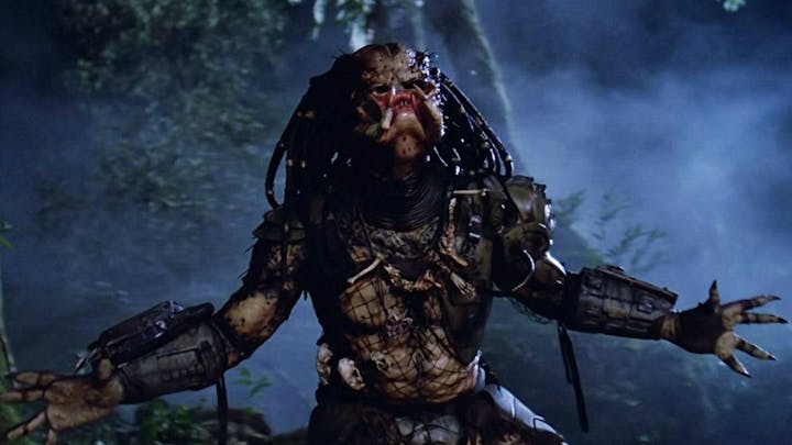 A menacing extraterrestrial creature with dreadlocks and futuristic armor in a misty jungle environment.