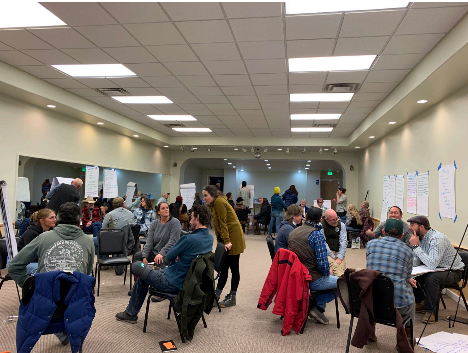 A group of people engaged in a meeting or workshop with papers on walls.