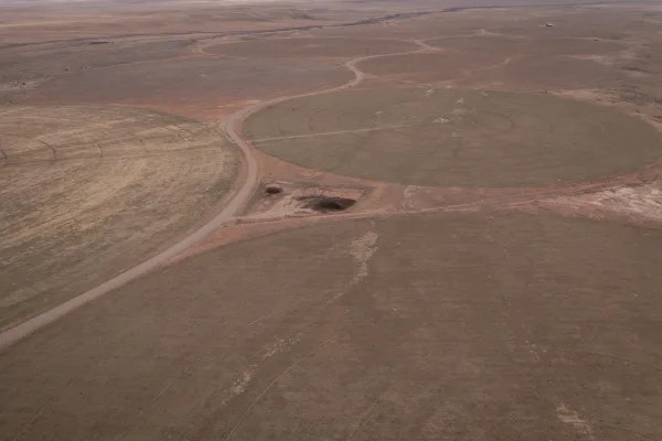 Aerial view of a barren landscape with circular patterns and a sinkhole.