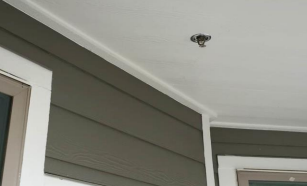 An overhead sprinkler mounted on a house's eave.