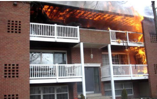 Apartment building with a fiery blaze engulfing the top floor balcony.