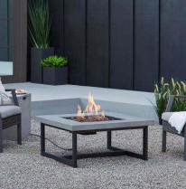 Outdoor fire pit with flames, surrounded by chairs on a patio.
