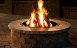 A fire pit with flames, surrounded by bricks, at night.
