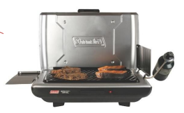 A portable propane grill with steaks cooking on it.