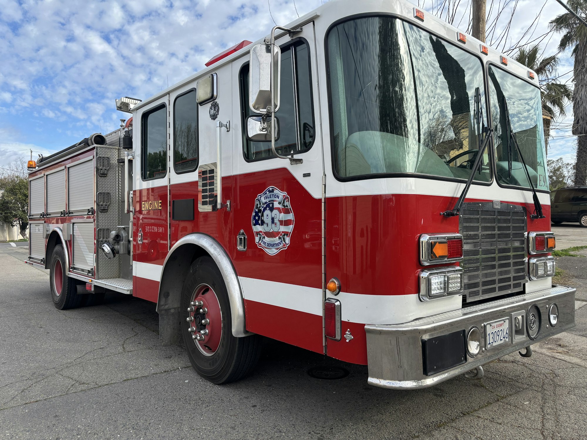A red and white fire truck parked on a street under a partly cloudy sky.