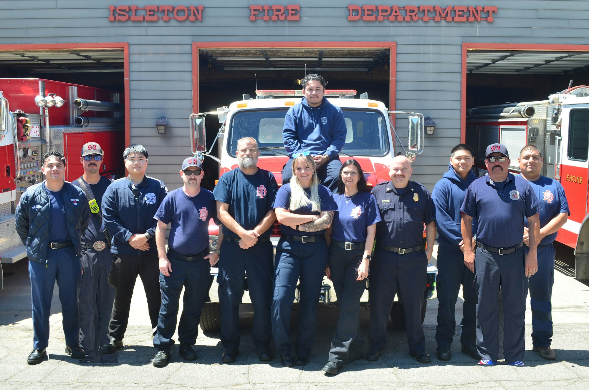 A group of people posing in front of a fire truck at the "Isleton Fire Department."