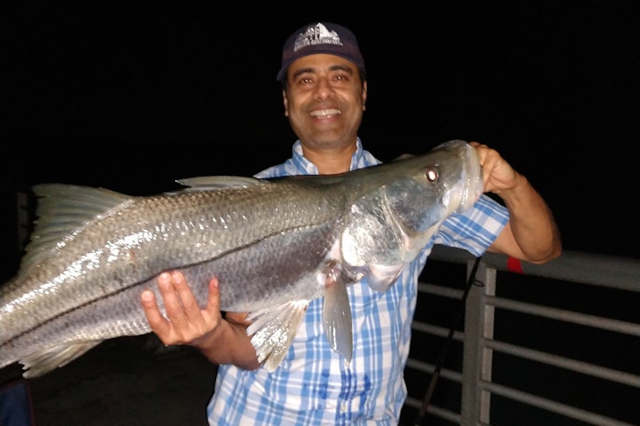man holding large snook at night