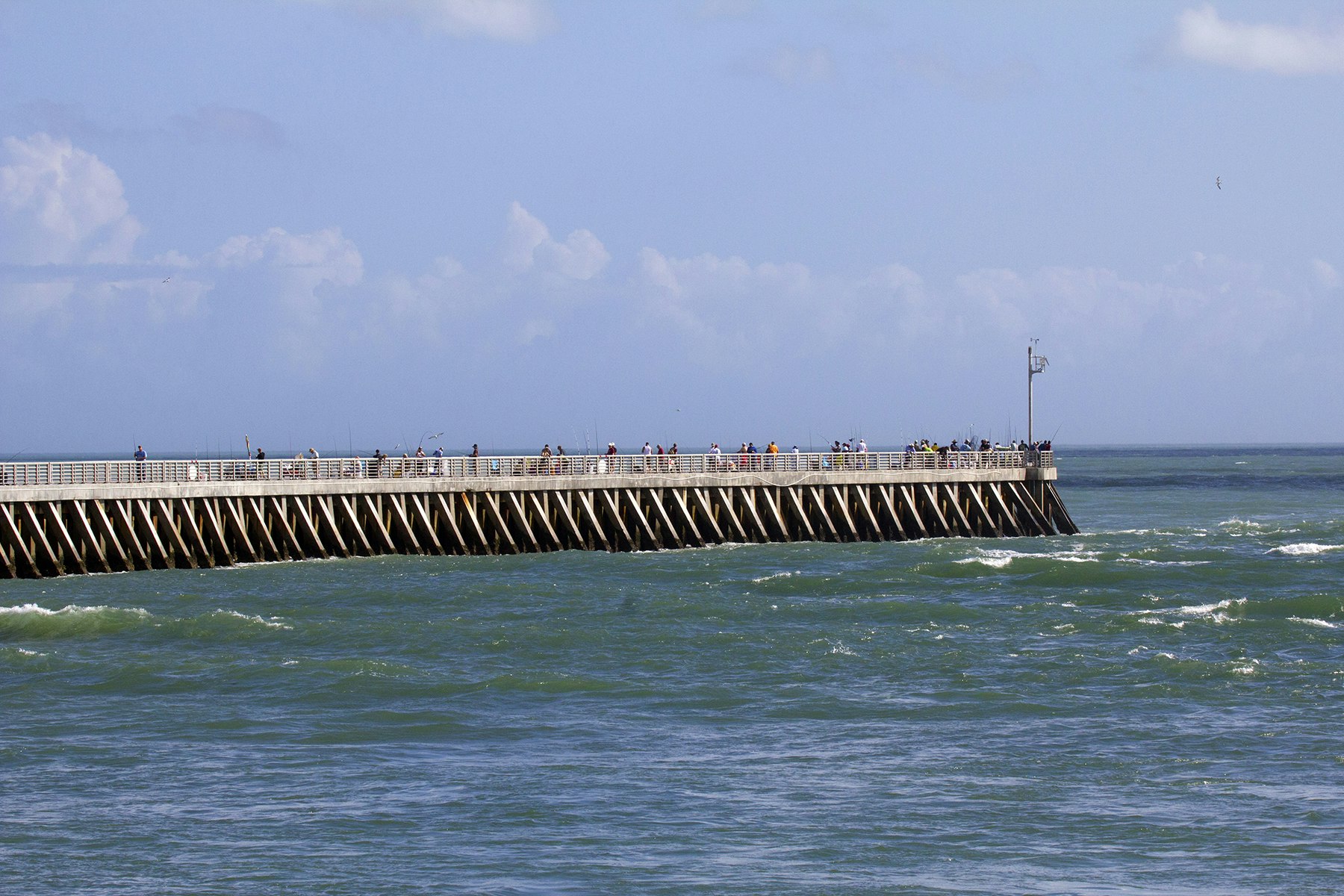 jetty jutting into ocean with people on fishing deck