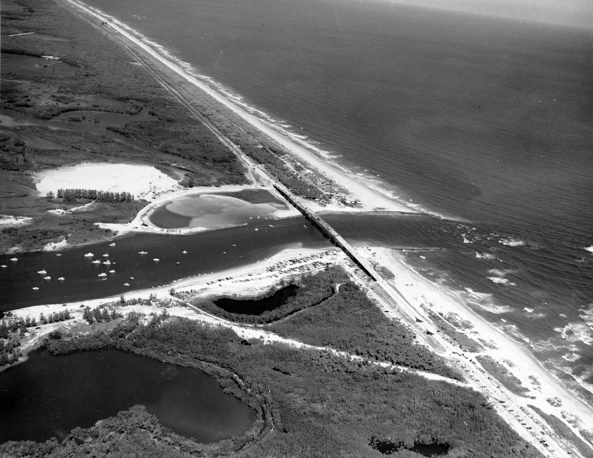 aerial view of the inlet looking North with new bridge completed on opening day with many boats in the inlet channel