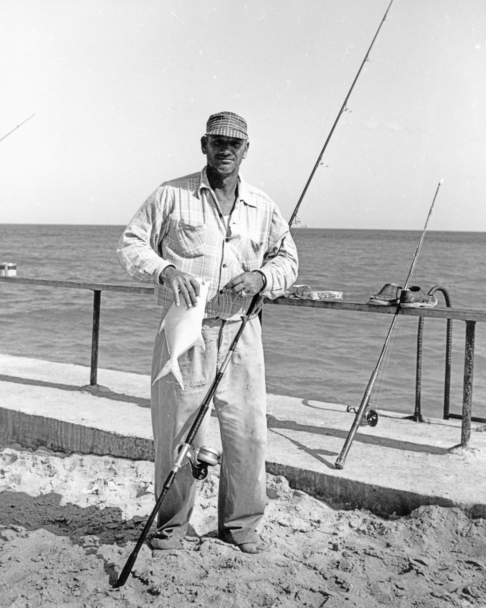 Fisherman standing with his rod and fish he caught on the jetty