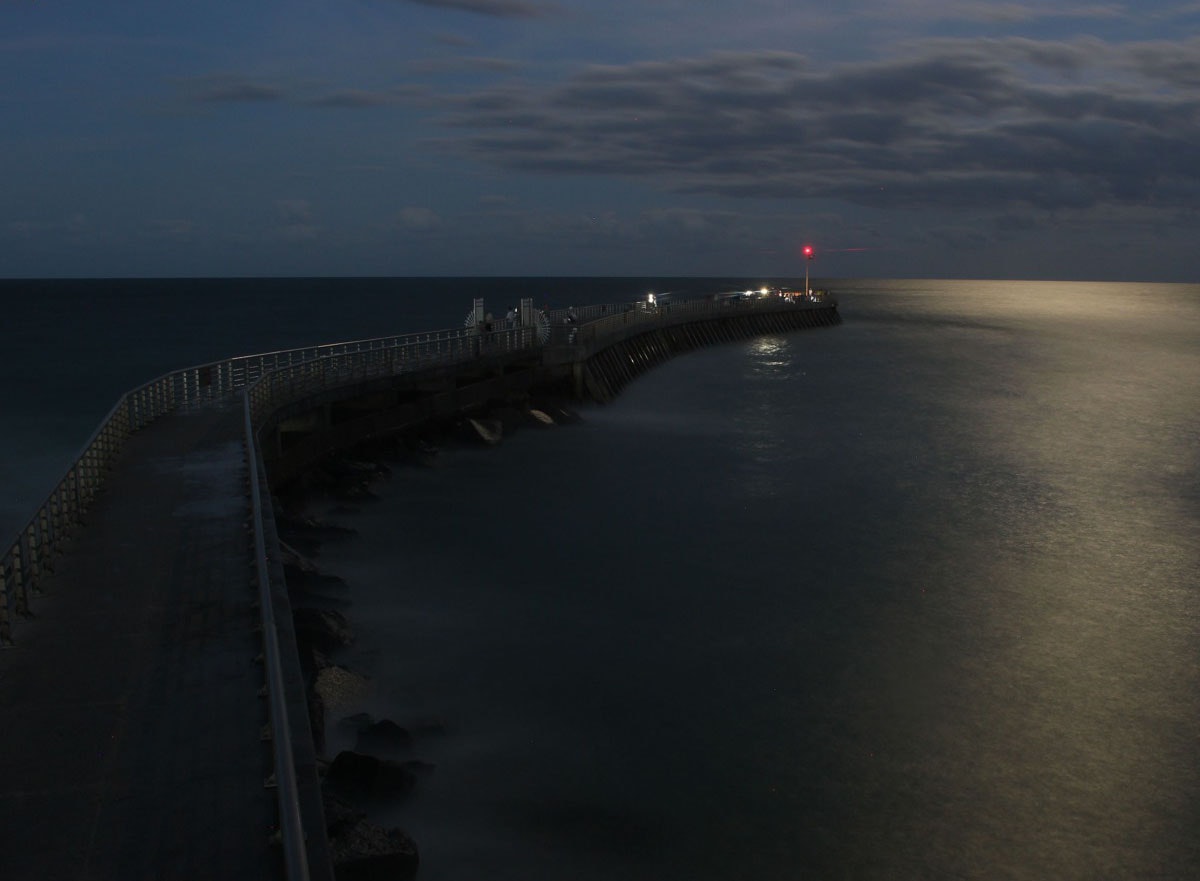 moonlight photo of north jetty with glowing red navigation light at tip