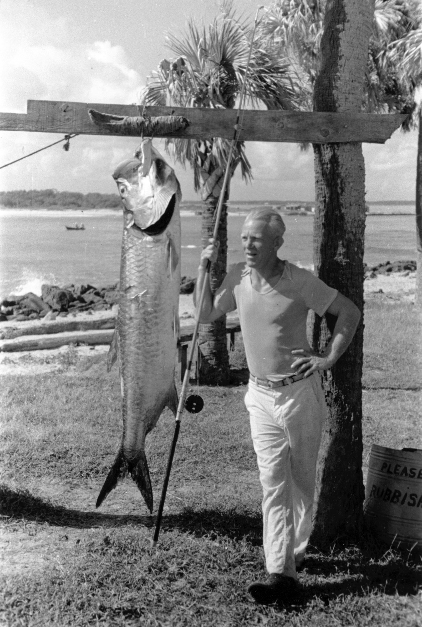 historical photo from mid-1930s of man displaying a massive tarpon caught fishing at the inlet