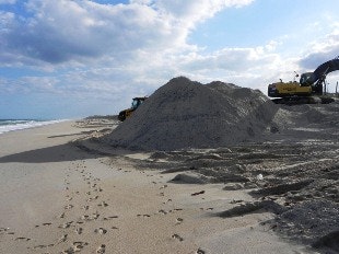 mound of sand on beach with heavy equipment