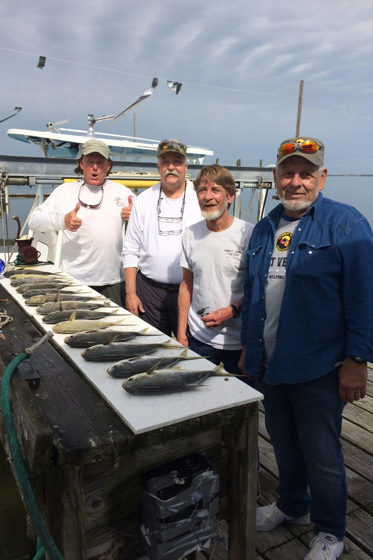 Four men standing behind a row of pompano on fish cleaning station