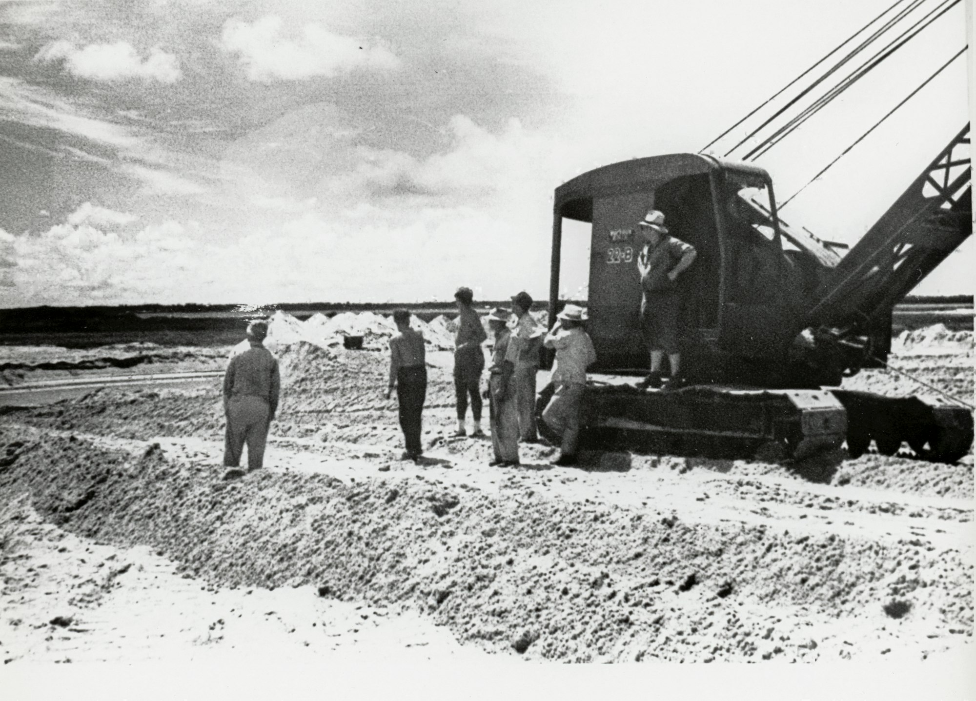 Excavator on the sand with workman around it