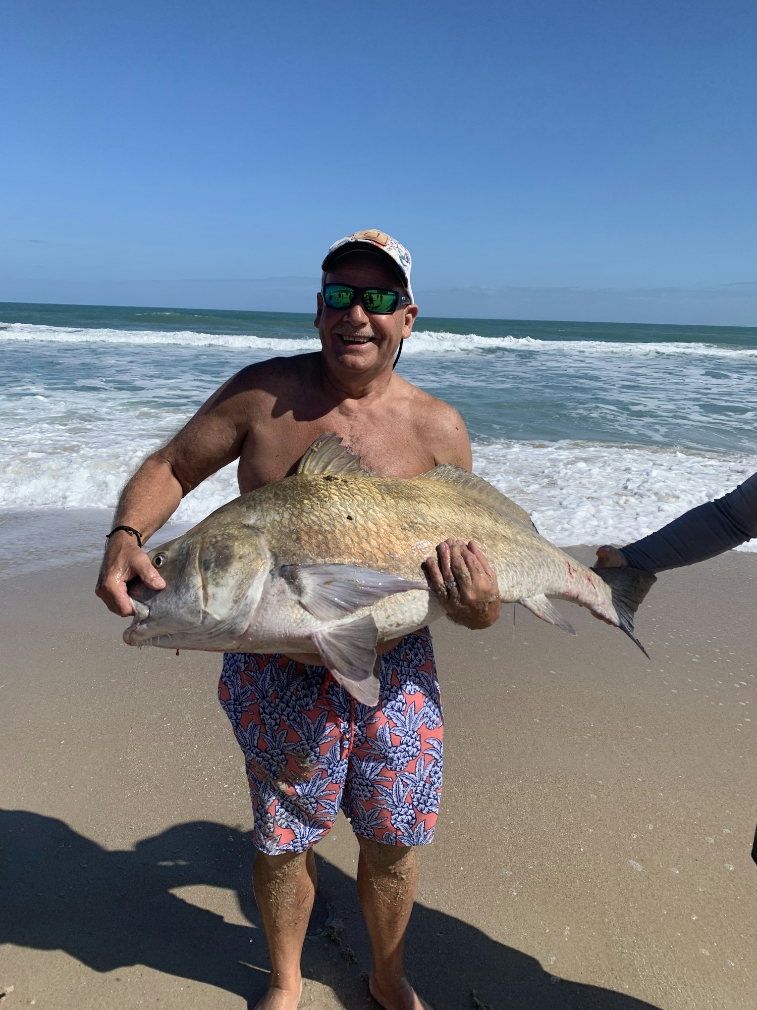 May contain: animal, fish, sea life, accessories, glasses, face, head, person, photography, portrait, adult, male, man, clothing, hat, nature, outdoors, sea, water, beach, coast, and shoreline