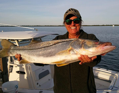woman holding snook on boat