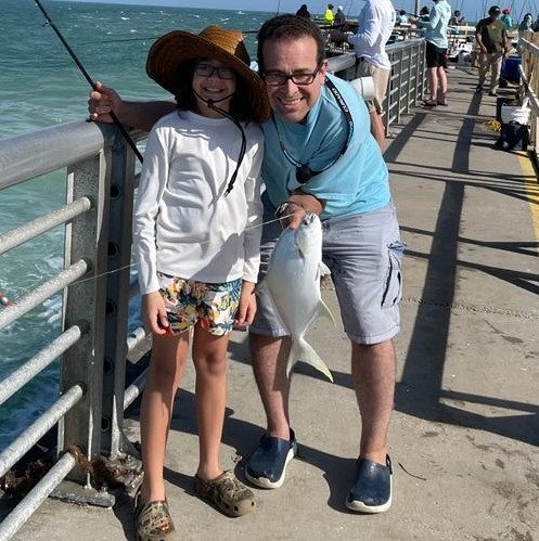 May contain: clothing, shorts, fishing, leisure activities, outdoors, water, waterfront, face, head, person, photography, portrait, accessories, glasses, adult, male, man, footwear, shoe, glove, and hat
