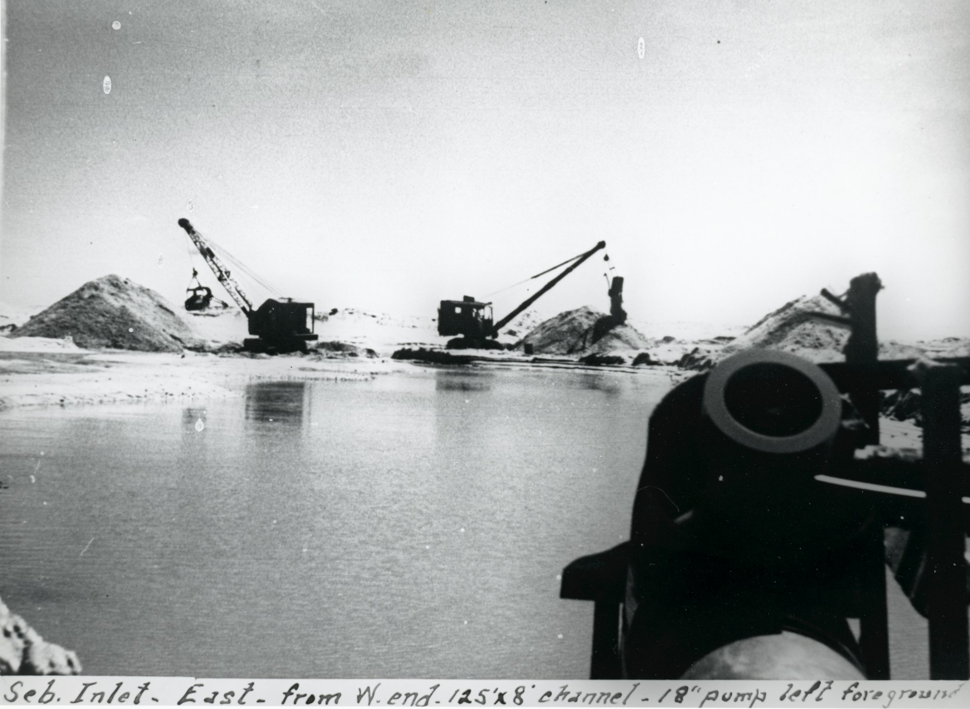 Two excavators moving sand in background with water and 18 inch pump in foreground