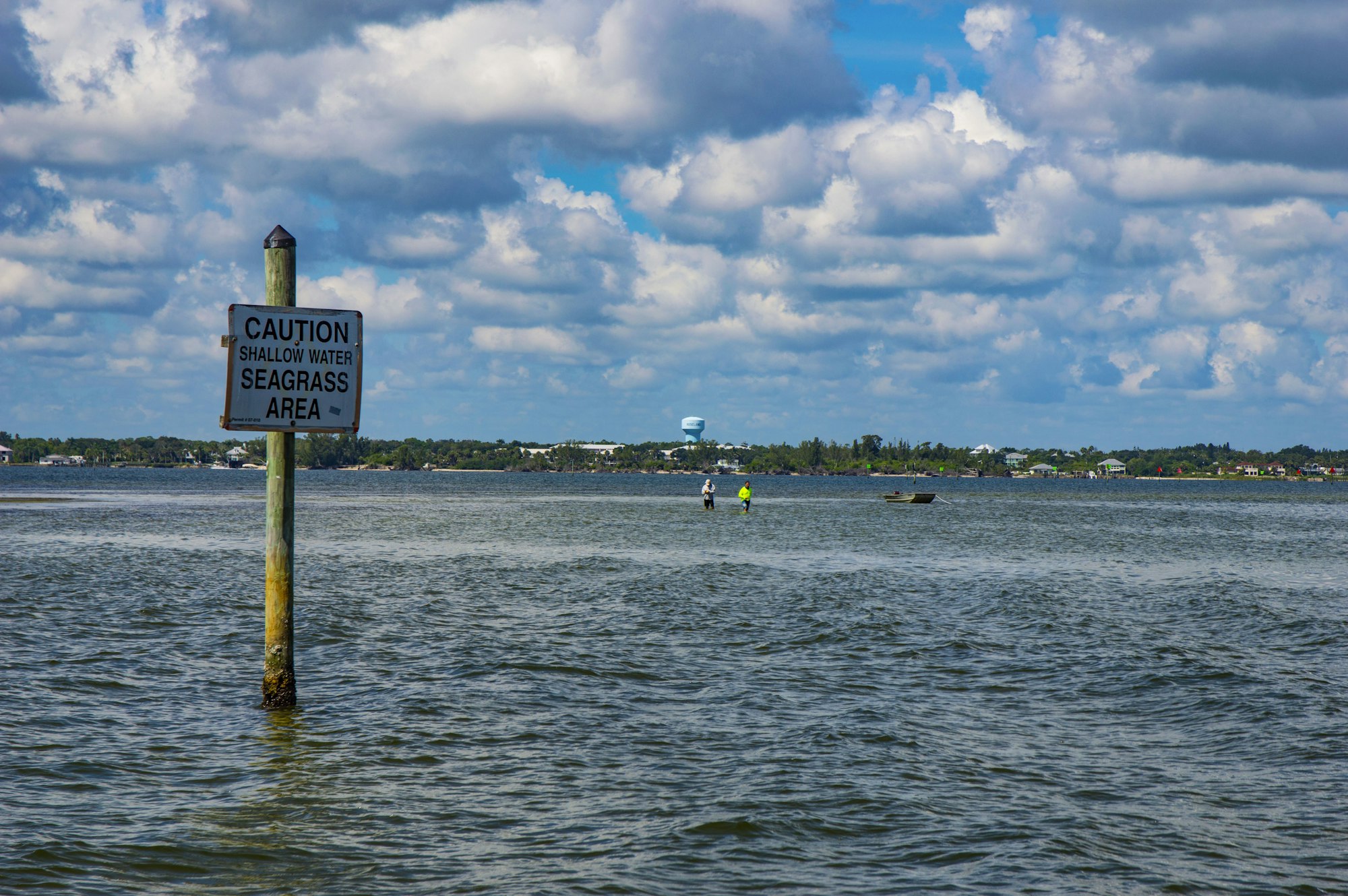 seagrass zone caution sign in indian river lagoon with marine biologists doing field work