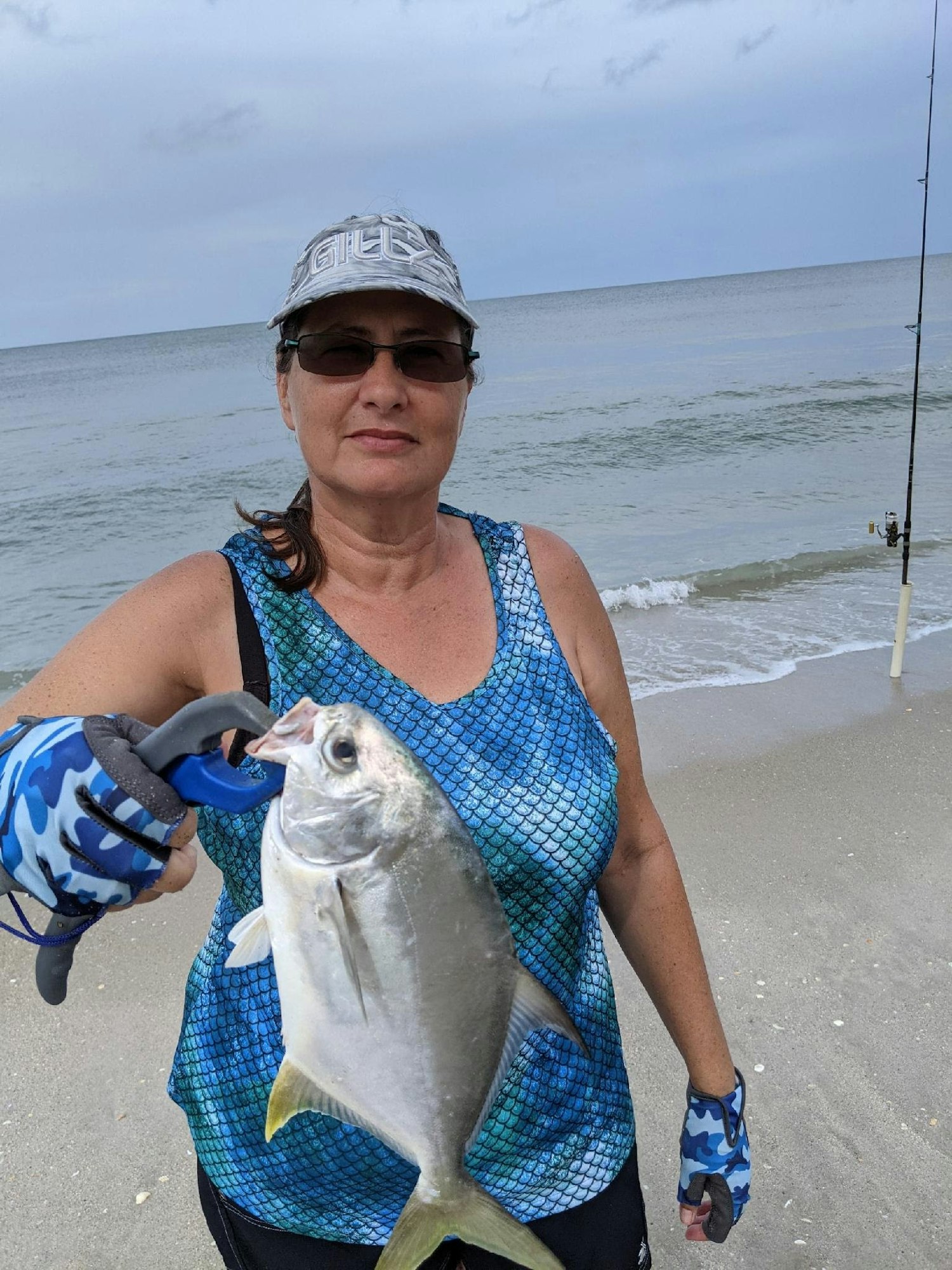 May contain: face, head, person, photography, portrait, beach, coast, nature, outdoors, sea, shoreline, water, soil, clothing, glove, animal, fish, sea life, fishing, leisure activities, adult, female, woman, baseball cap, cap, hat, bonito, and tuna
