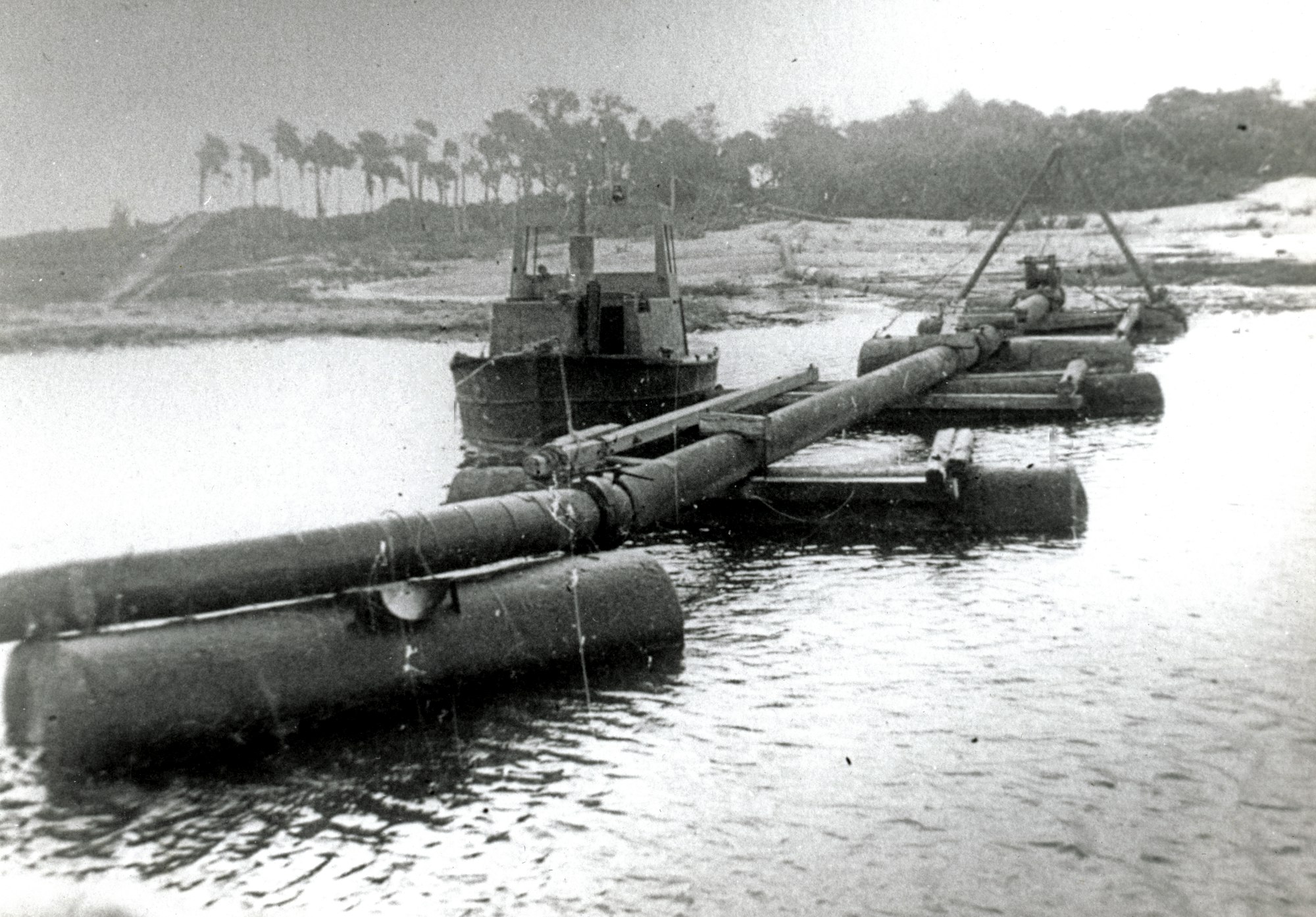 floating dredge pipe suspended over water with a skiff