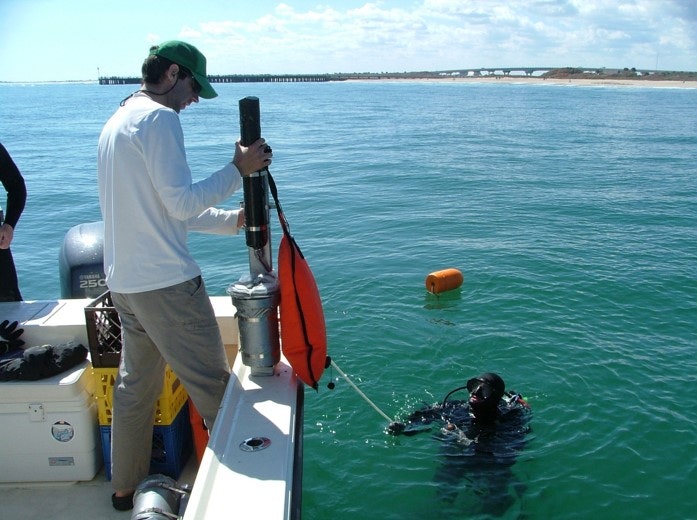 man in boat handling equipment to diver in water