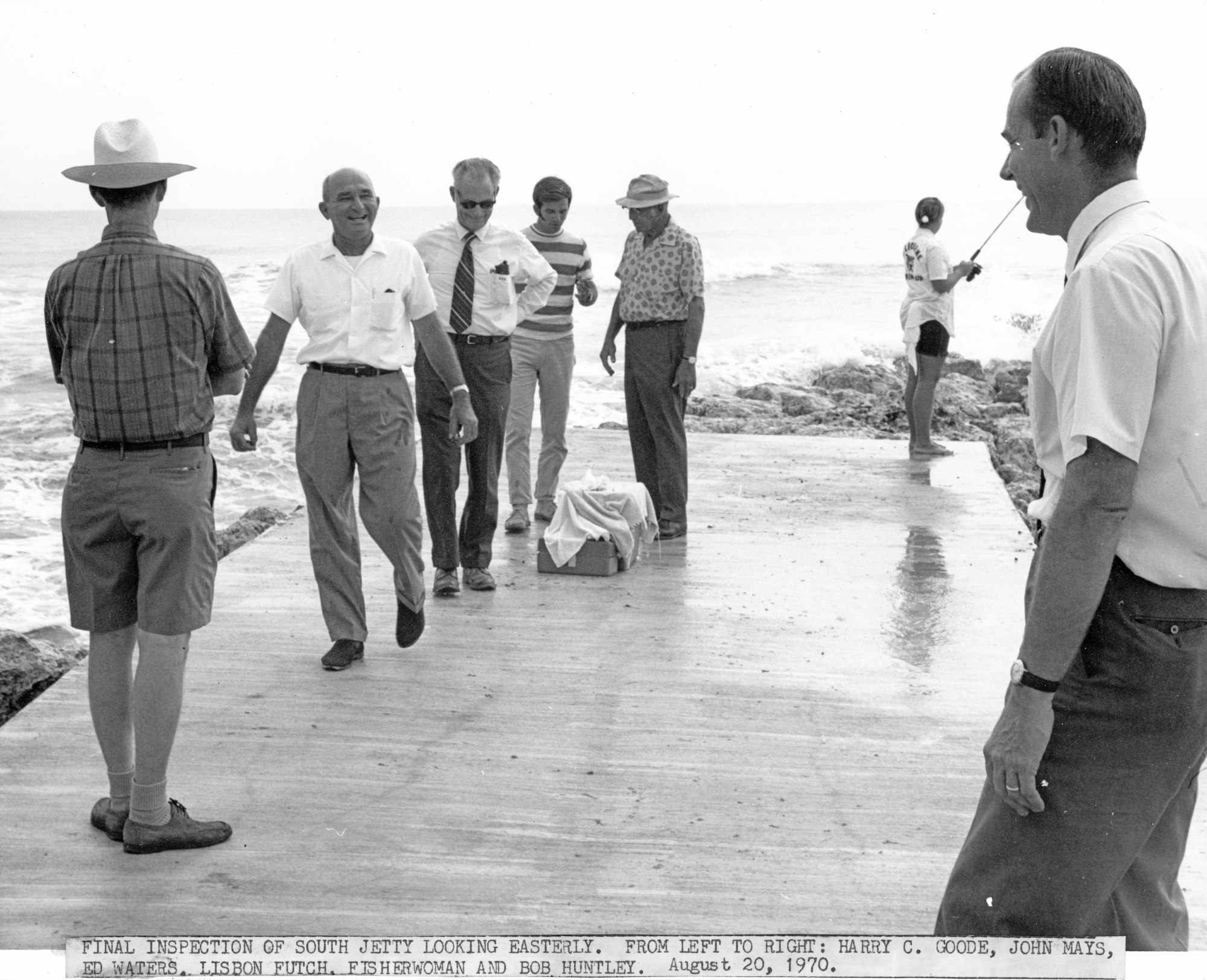 a group of men inspecting the south jetty with fisherman in background