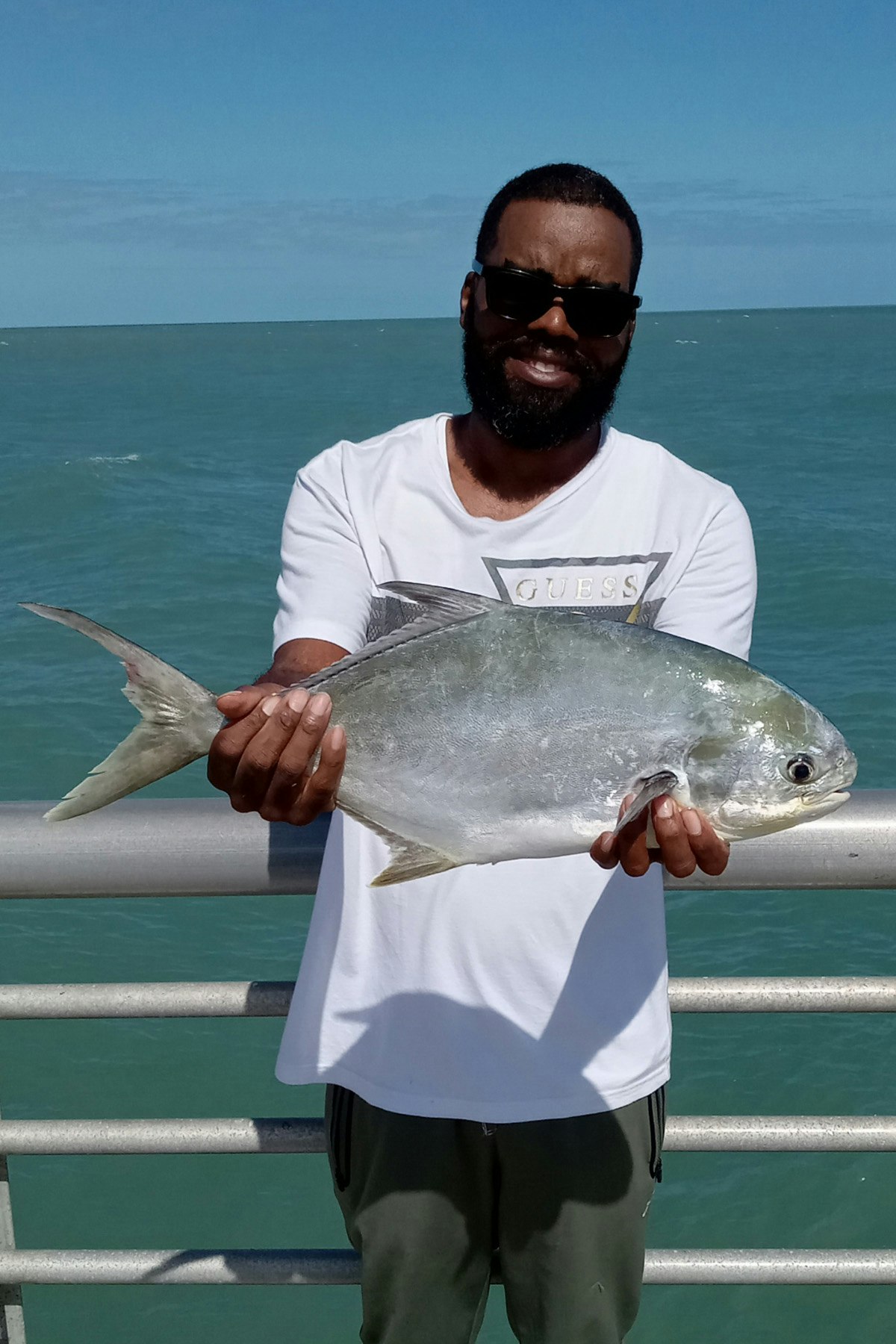 May contain: fish, sea life, animal, sunglasses, accessories, person, man, adult, male, bonito, tuna, fishing, water, outdoors, leisure activities, shorts, clothing, face, and head