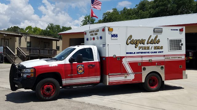 An EMS vehicle parked in front of a building with flags.